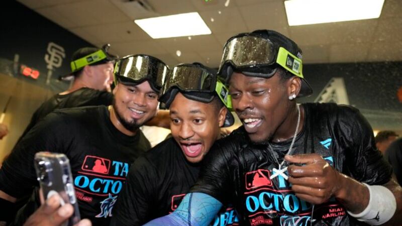 Miami Marlins' Tanner Scott, right, takes a selfie with teammates during a locker room...
