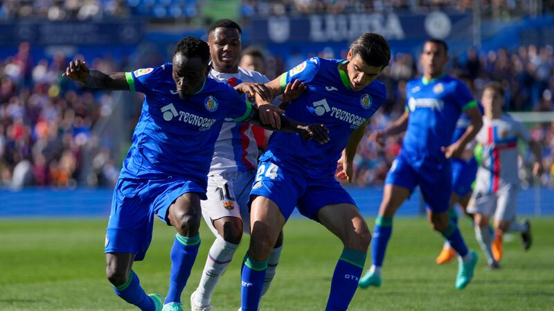 Barcelona's Ansu Fati, centre, fights for the ball with Getafe's Djene Dakonam, left, and...