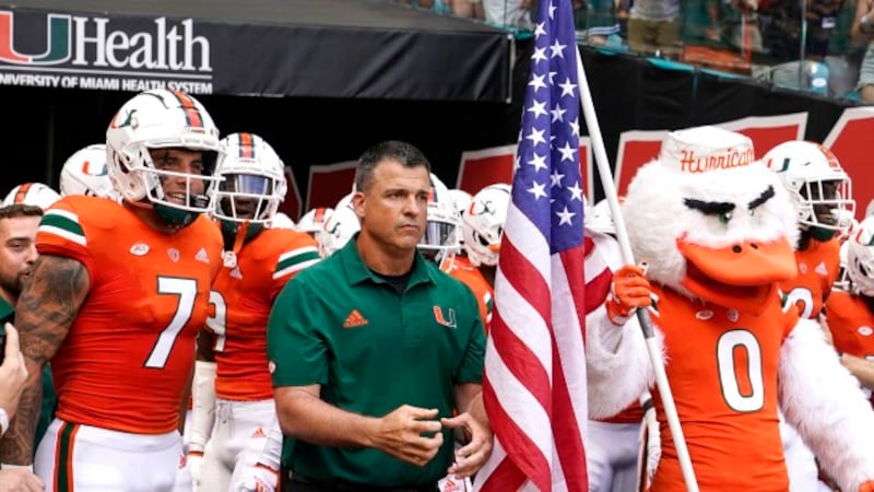 Miami head coach Mario Cristobal, center, prepares to run onto the field before an NCAA...