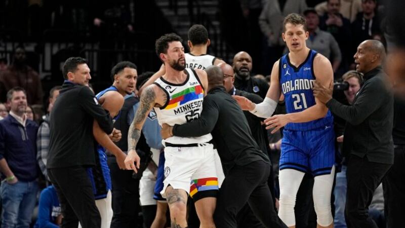 Minnesota Timberwolves guard Austin Rivers, middle, is held back after participating in a...