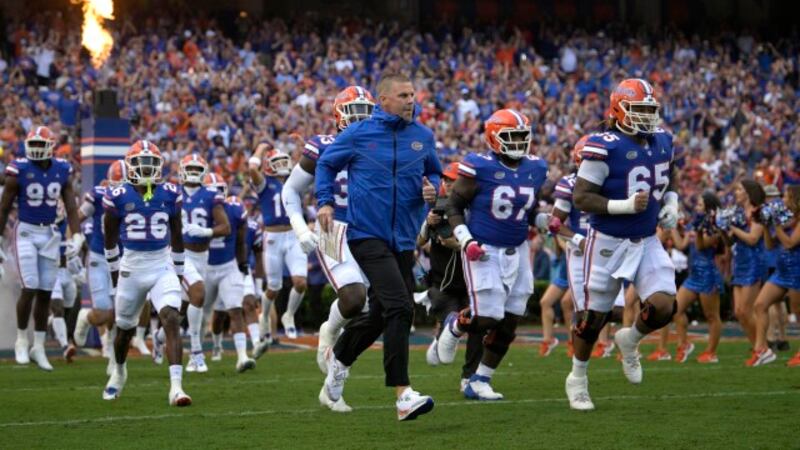 Florida head coach Billy Napier, center, leads the team onto the field before an NCAA college...
