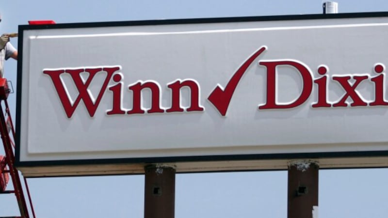 FILE - Mark Moore, of BriteLite Signs, paints a sign with the new Winn-Dixie logo, June 29,...