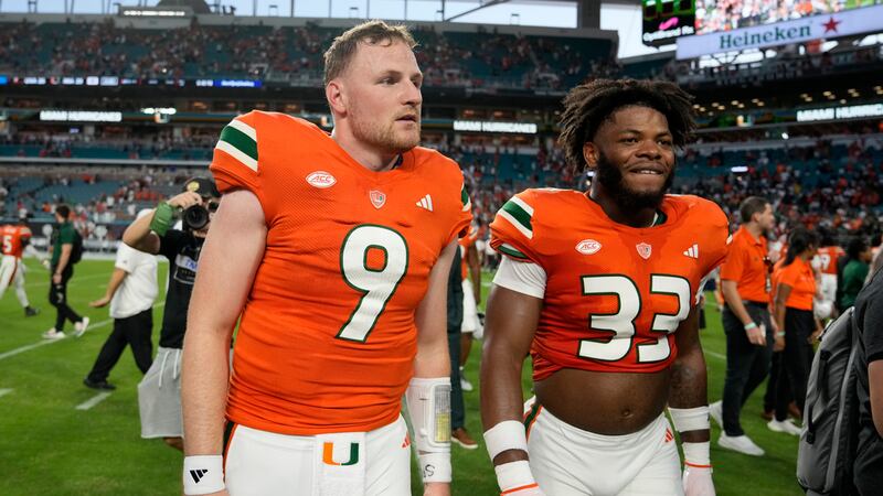 Miami quarterback Tyler Van Dyke (9) and linebacker Marcellius Pulliam (33) walk off the field...